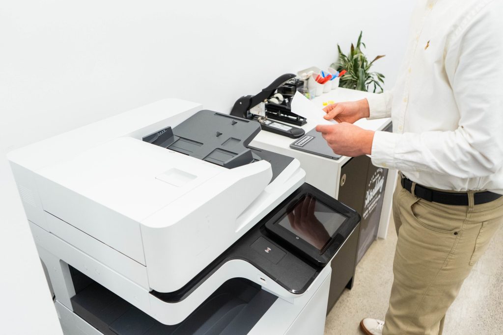 Boost Productivity with Wireless Printers & Copiers - A businessman in a modern office using a copier machine, efficiently handling documents.